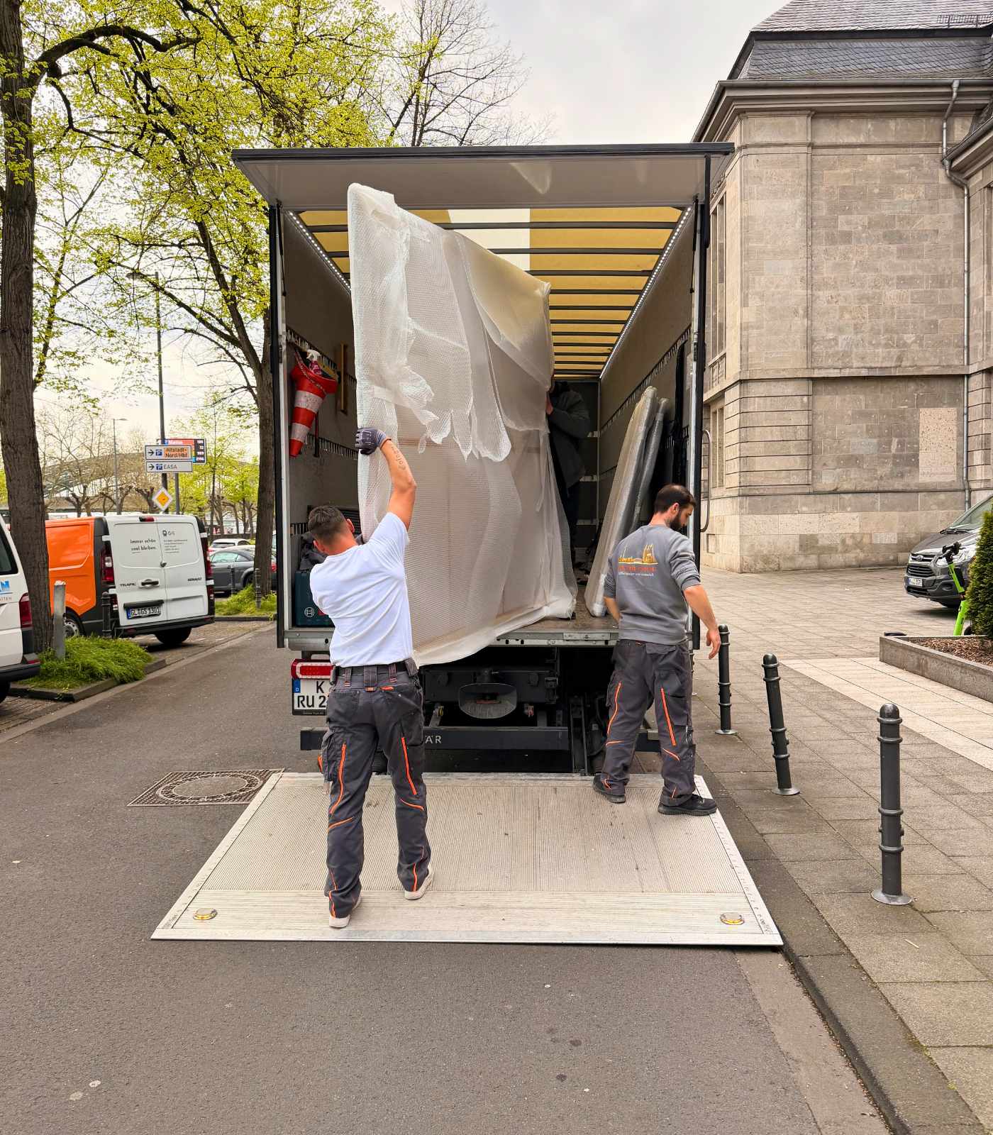 Mitarbeiter von Reuter Umzüge entladen große Möbelstücke aus einem Umzugs-Lkw in Köln.