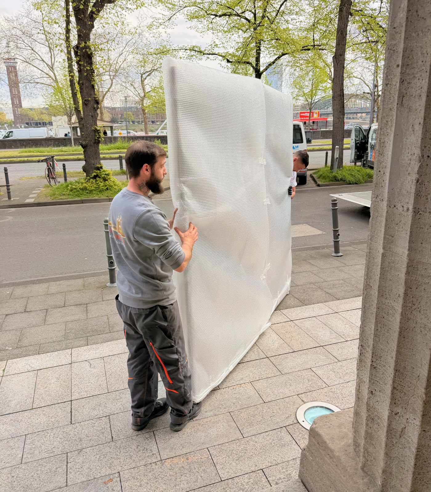 Mitarbeiter von Reuter Umzüge tragen einen verpackten Gegenstand für einen sicheren Möbeltransport.