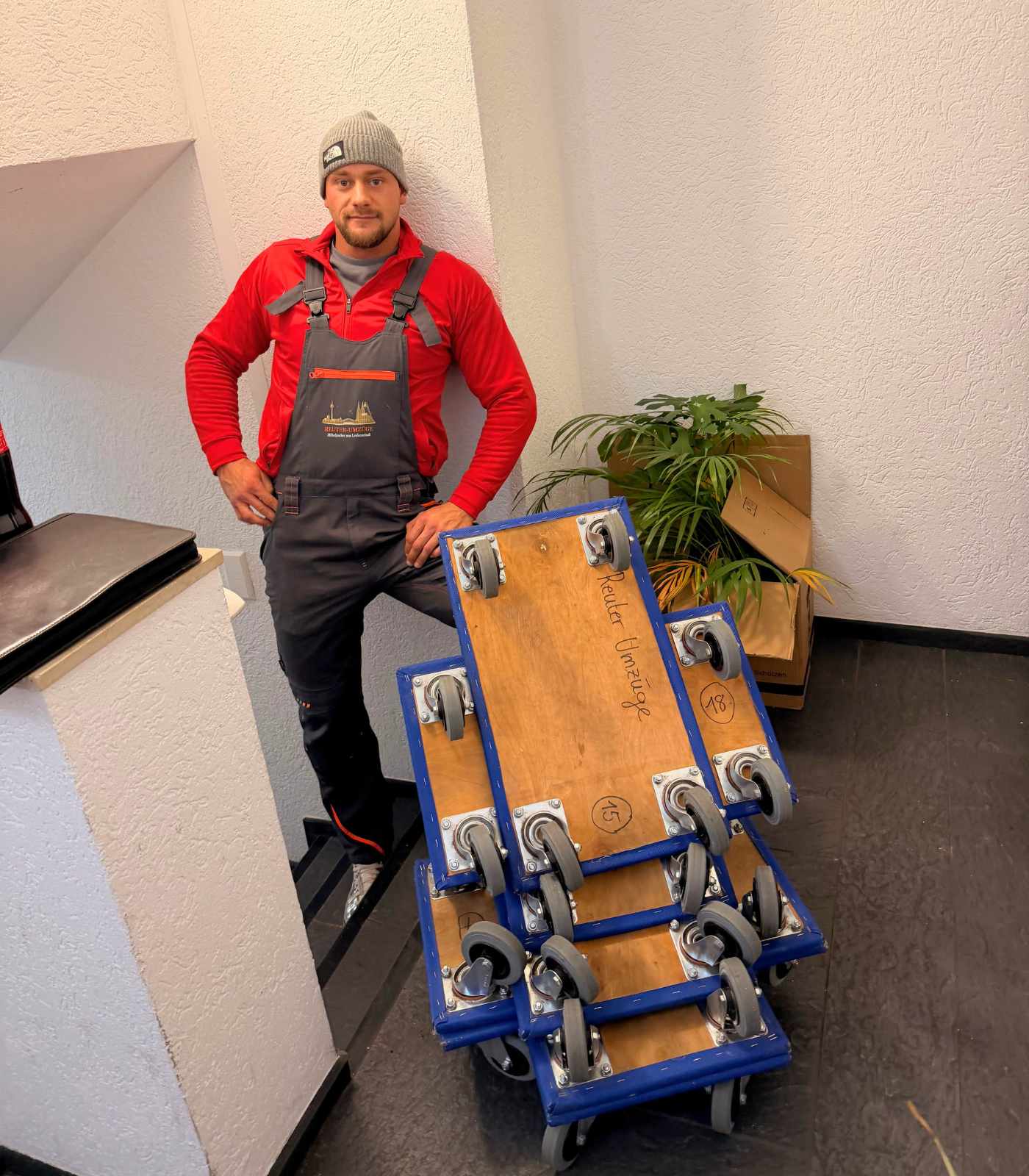 Ein Mitarbeiter von Reuter Umzüge präsentiert professionelle Rollbretter für den sicheren Möbeltransport.