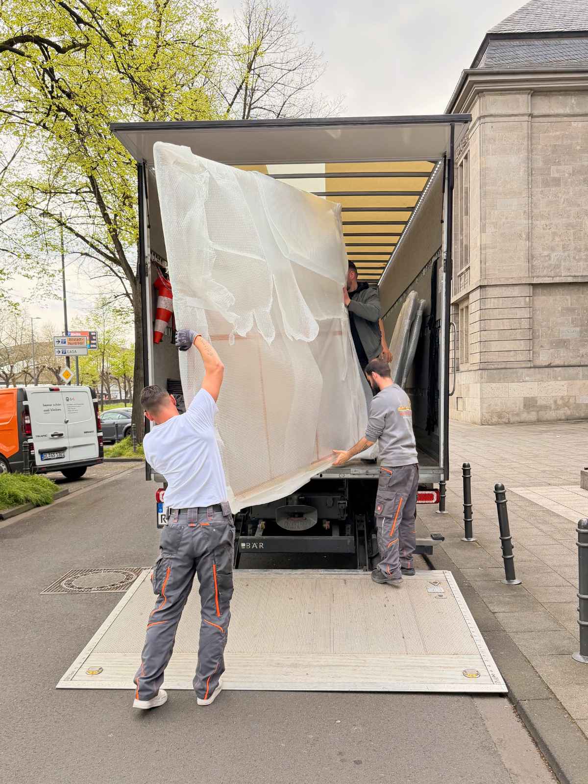 Das Team von Reuter Umzüge lädt ein große, geschützte Leinwand in den Umzugswagen. Als erfahrenes Umzugsunternehmen Köln sorgt Reuter Umzüge für sicheren Möbeltransport.