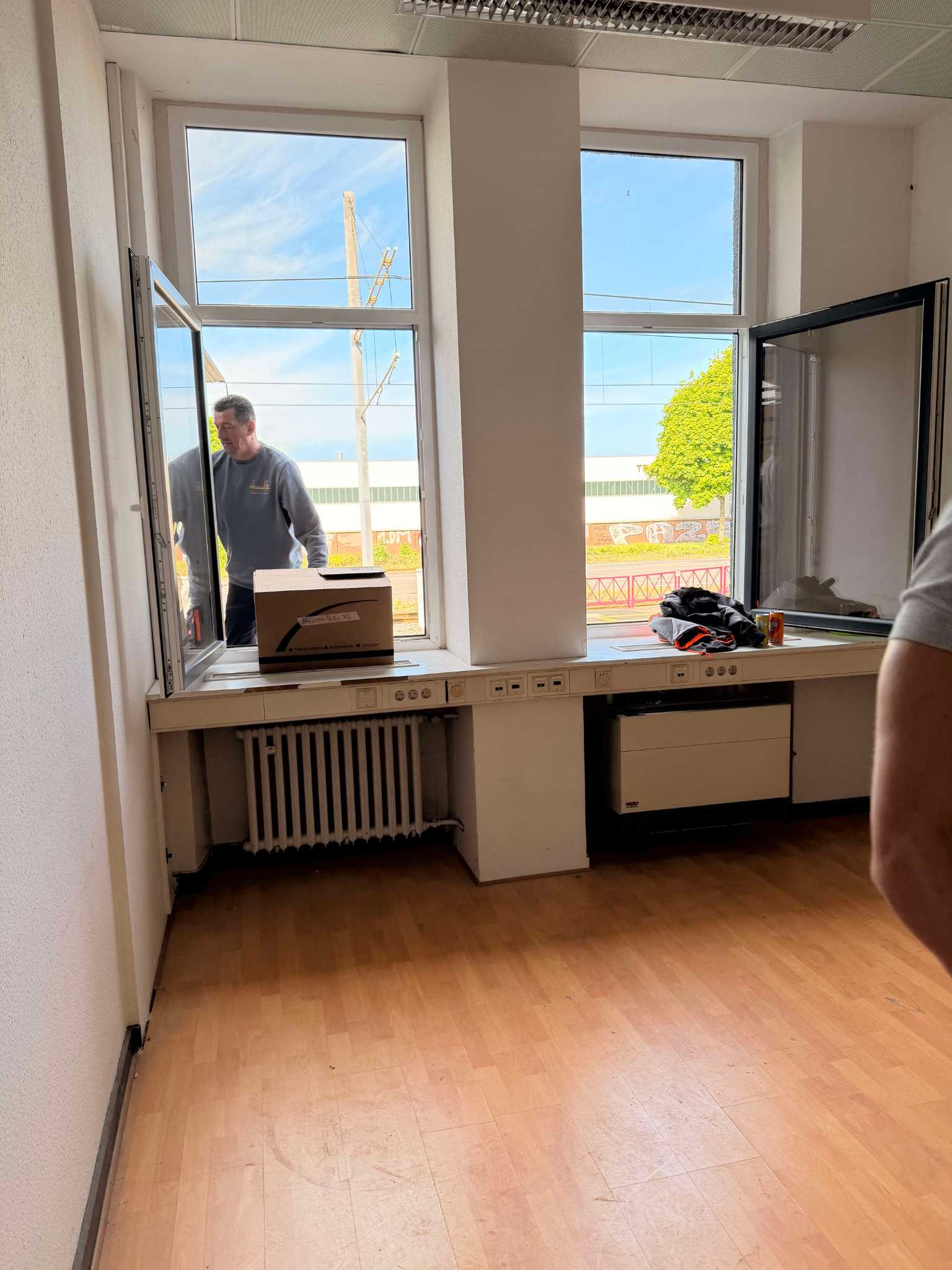 Während eines Büroumzugs in Köln werden Büroräume von Reuter Umzüge professionell geräumt. Ein Umzugskarton wird durch das geöffnete Fenster in Empfang genommen.